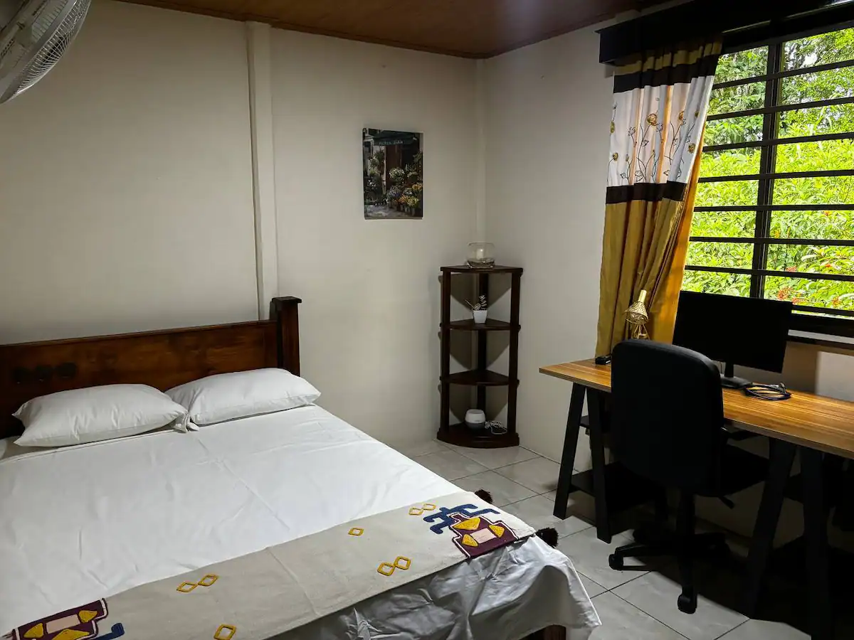 Spacious bedroom with a full bed, desk and monitor